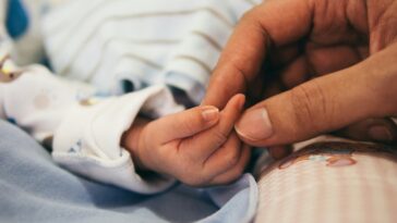 father holding new born hand